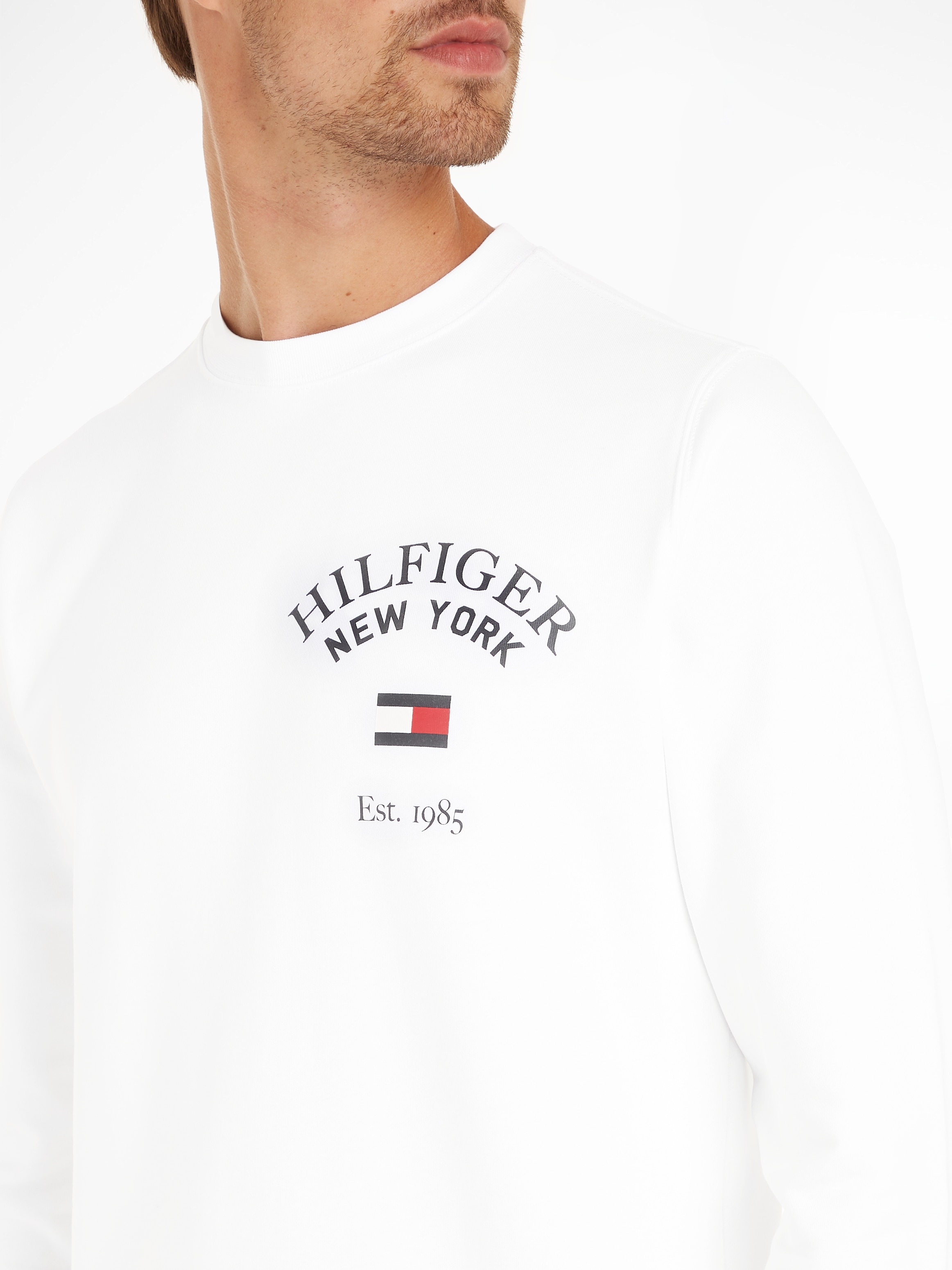 Tommy Hilfiger Sweatshirt ARCHED Logodruck der | BAUR modischem bestellen SWEATSHIRT«, VARSITY auf mit »WCC Brust ▷